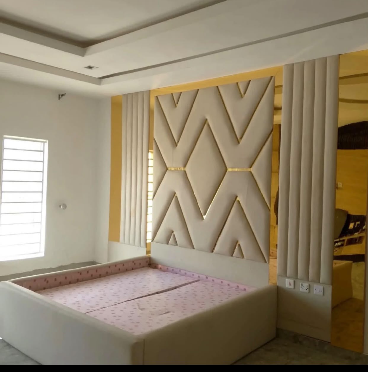 Upholstered bed with geometric headboard and gold trim